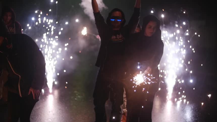 People walking as fireworks are going off at night
