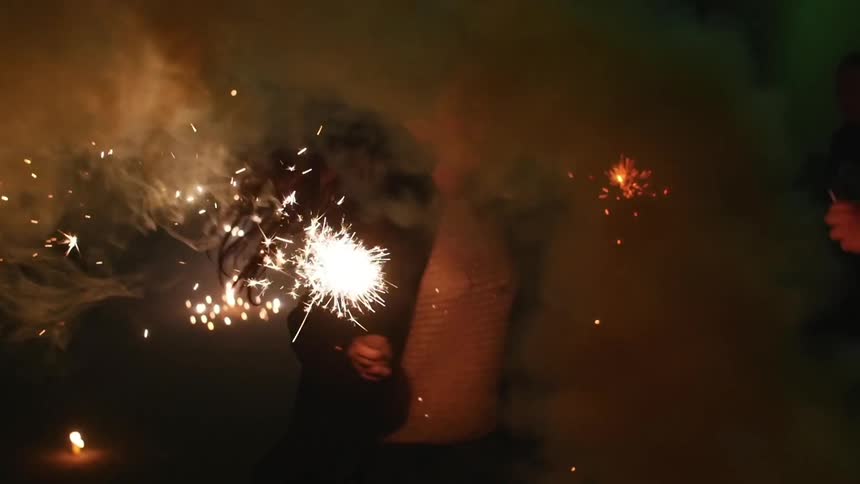 People celebrating and running with sparklers at night