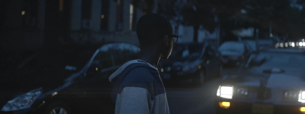 Boy standing in front of a car walks off