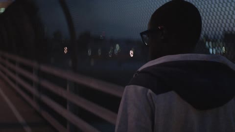 Man walking over a bridge with a fence on his side