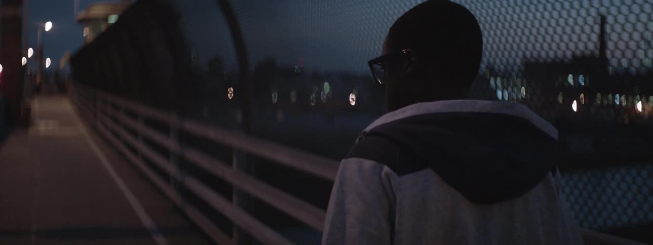 Man walking over a bridge with a fence on his side