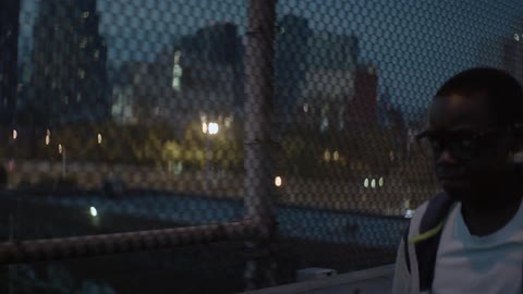 A person walking past a chain link fence