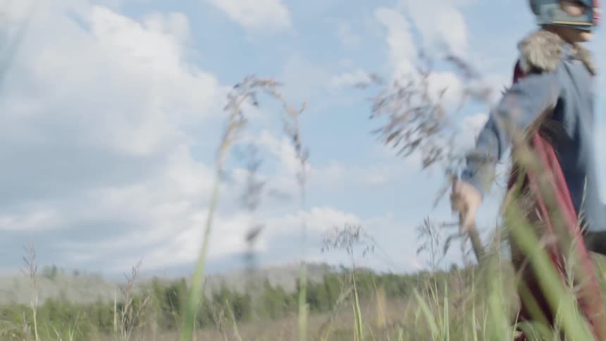 Boy in a costume plays in a rural field