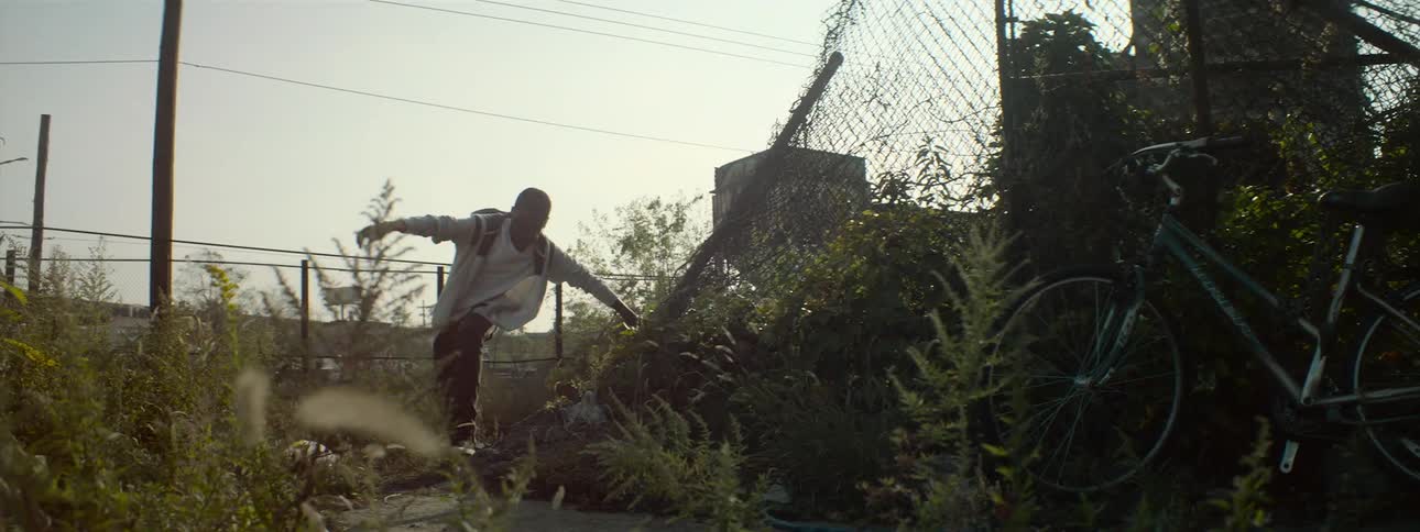 Boy climbs up and walks past a bike leaning on a fence