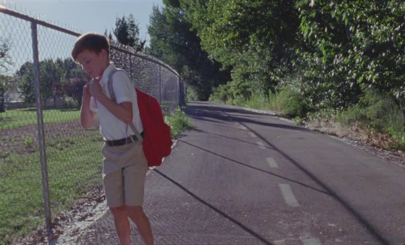 A child walks past the chain link fence