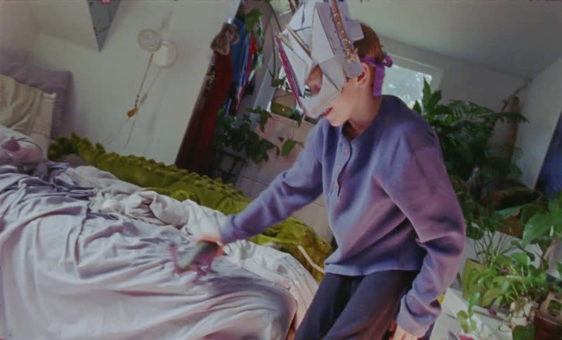 Boy wearing a mask plays with a toy dinosaur in his bedroom