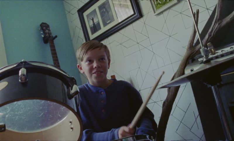 Young boy plays the drums and hits a cymbal