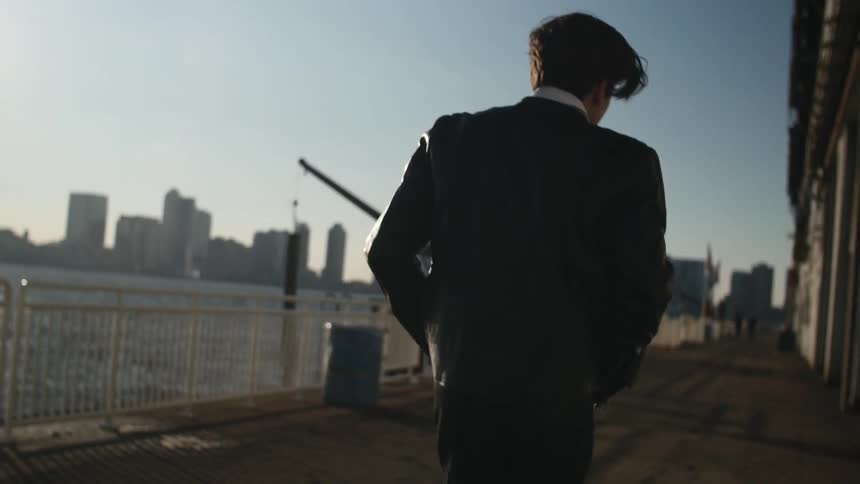 Man walking outside near the water by a building