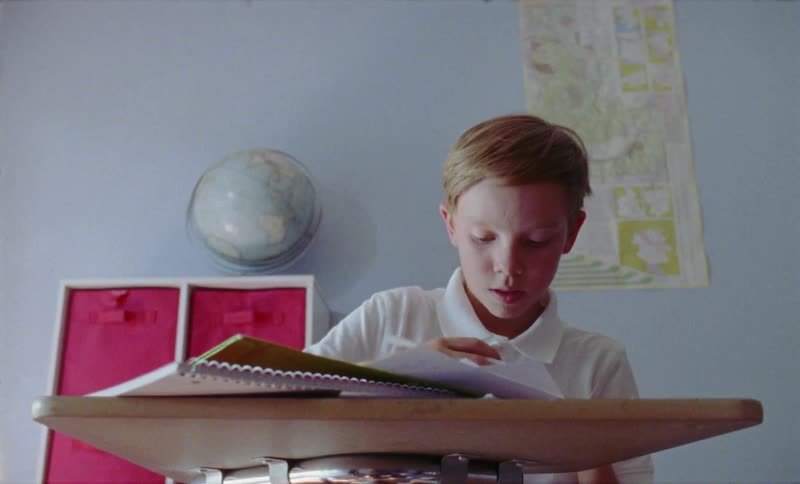 Boy writes in a notebook in a classroom