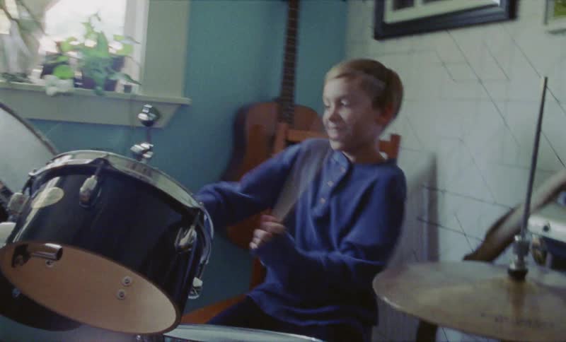 Little boy smiling and playing drums in living room