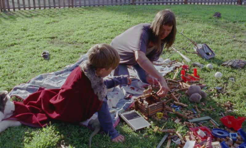 A mother and son are playing with toys in a yard during the day