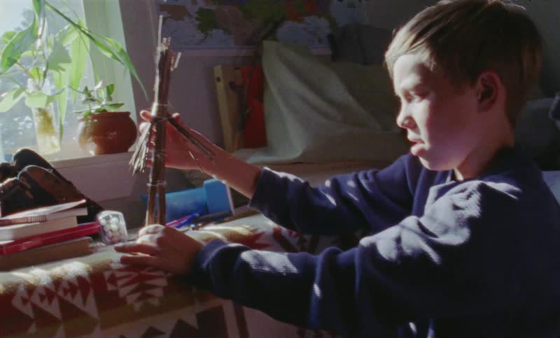 Child plays with a stick in his bedroom
