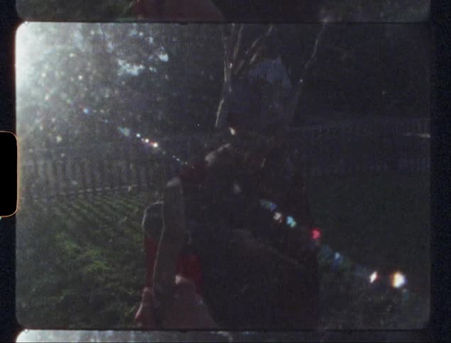 A boy is using a stick as a sword as he plays in a yard on a sunny day