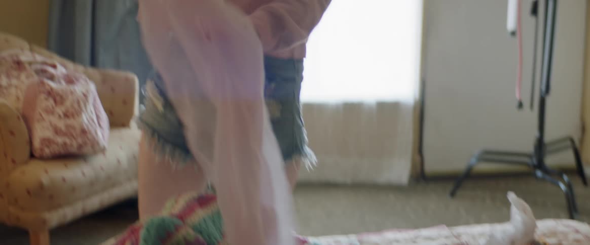 Woman tidies up a bedroom and places a piece of fabric on a lamp shade