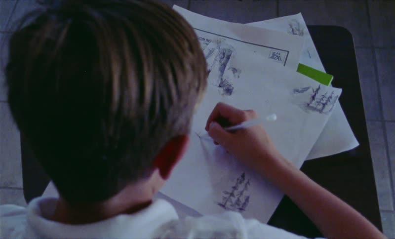 Child sitting at a desk scribbling on a piece of paper