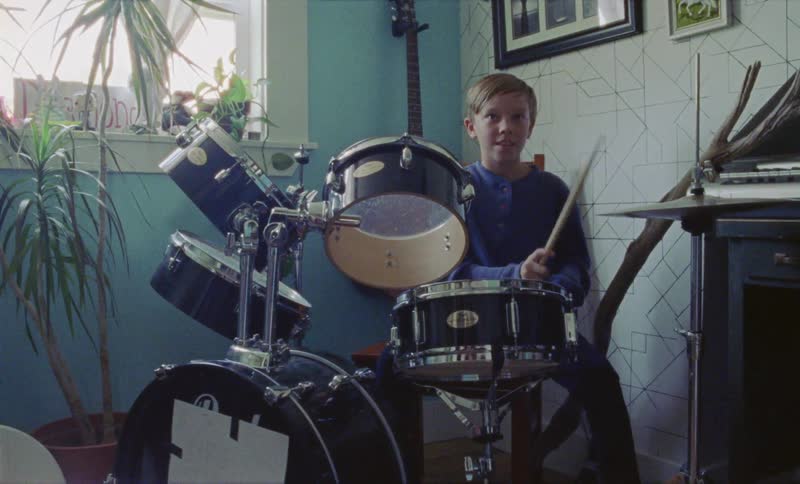 Child drums on a small drum kit