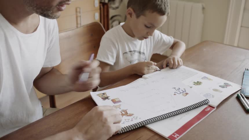 Man talks to a child as they both draw on a sketch pad