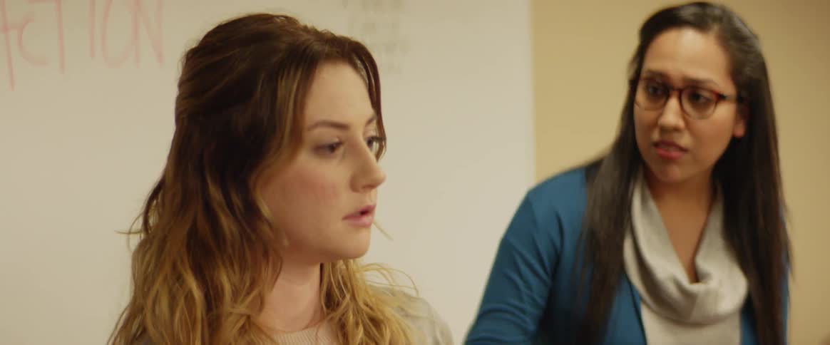 Two women sit and talk in a meeting
