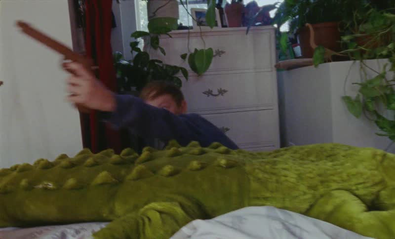 Young boy pretends to shoot a toy gun as he plays in a bedroom