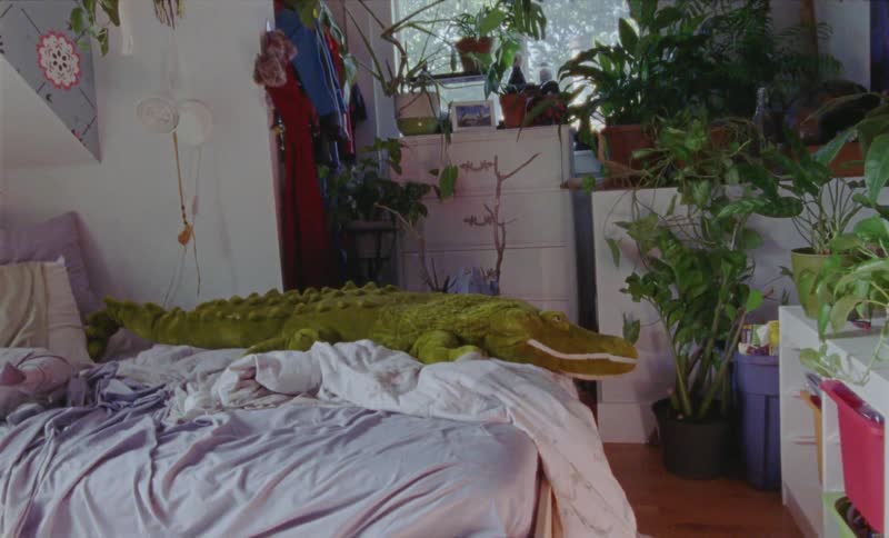 A toy alligator sits on a bed