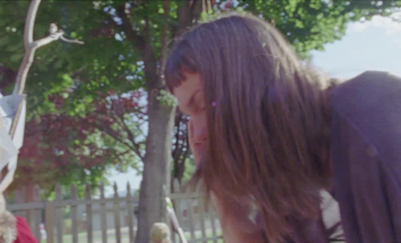 Child in mask and cape plays in yard with mom