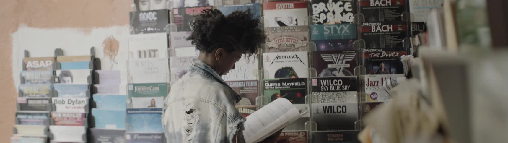 Person stands reading a book in a music store
