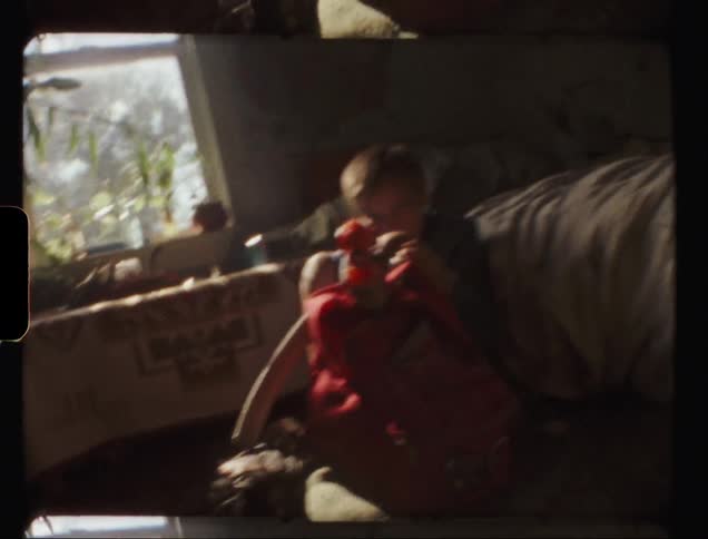Child plays with a toy gun in a bedroom
