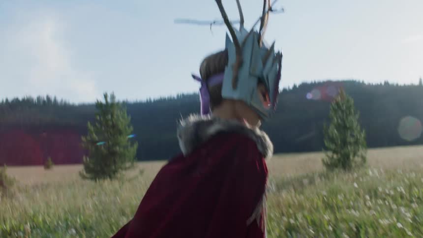 Child dressed as a gladiator walks through a large grassy field