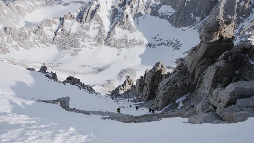 People hike up a large snowy mountain