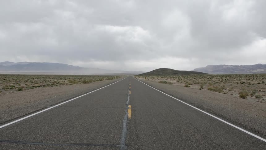 Straight road through the country with hills in the distance