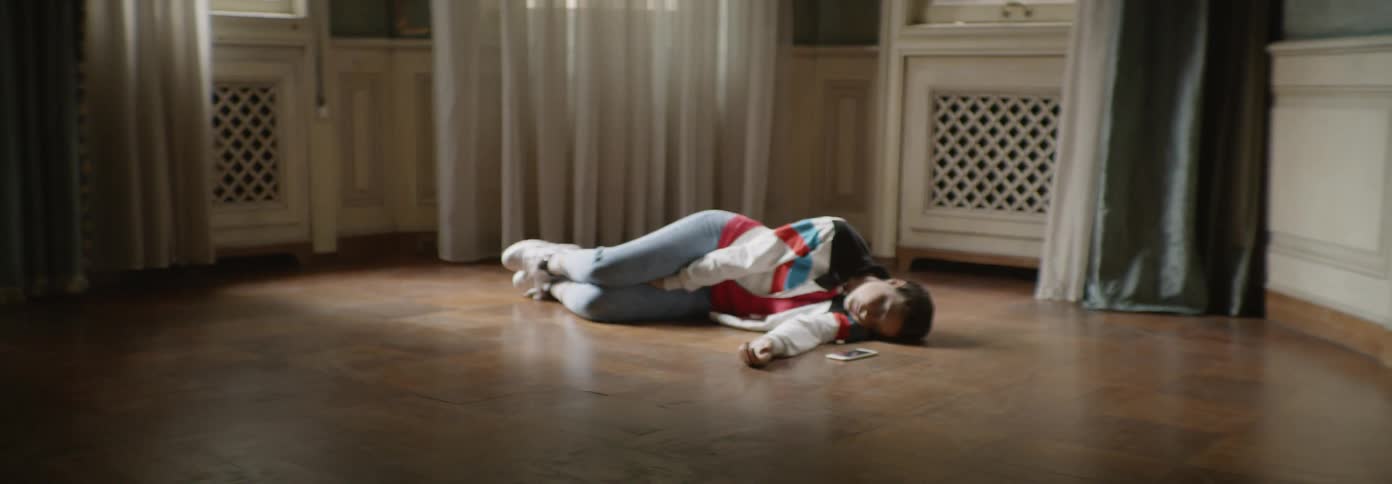 Woman laying on a floor in a room as if dead