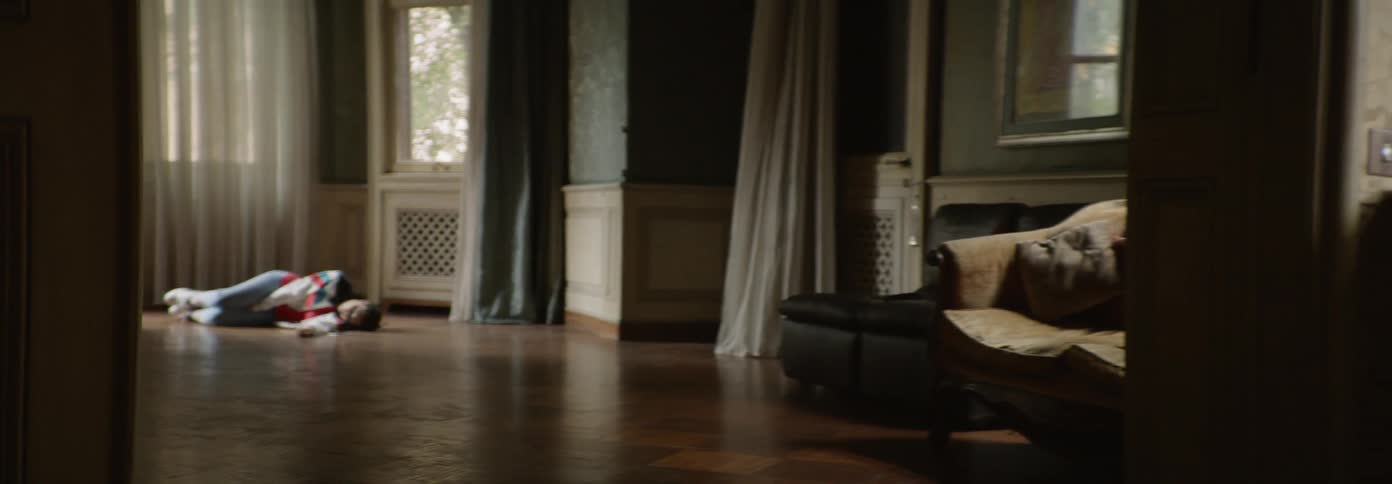 Woman laying on a floor in a room as if dead