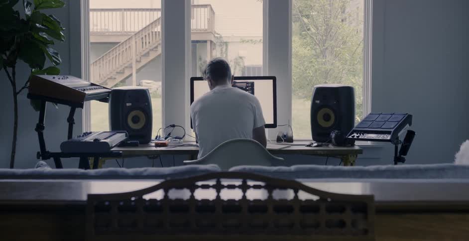 Man sits at a desk with a lot of computer equipment