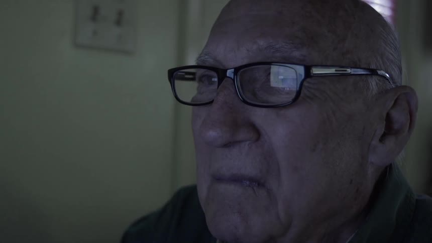 Elderly man stares into a screen