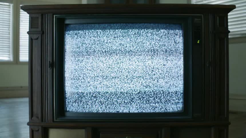 A vintage television flickers with static in an open room