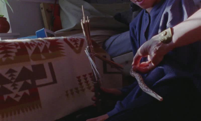 Woman holds a snake as she moves it near a young boy with a stick toy