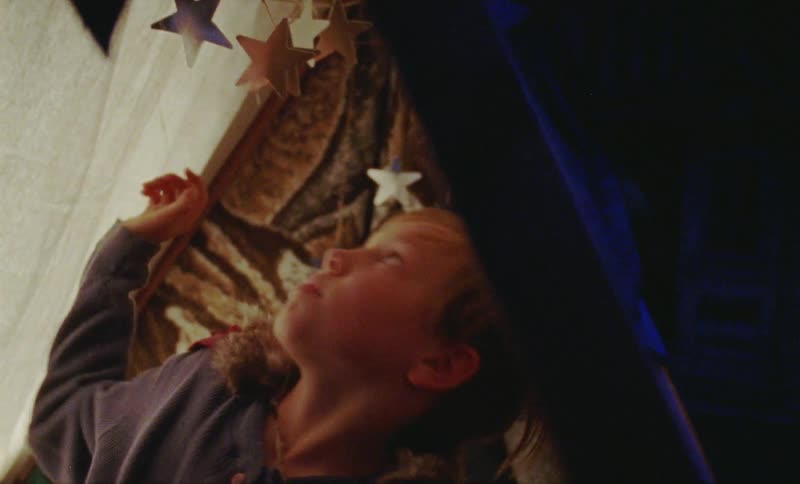 Child sits in a tent and touches silver stars
