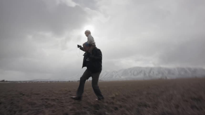 Man running outdoors with child on shoulders
