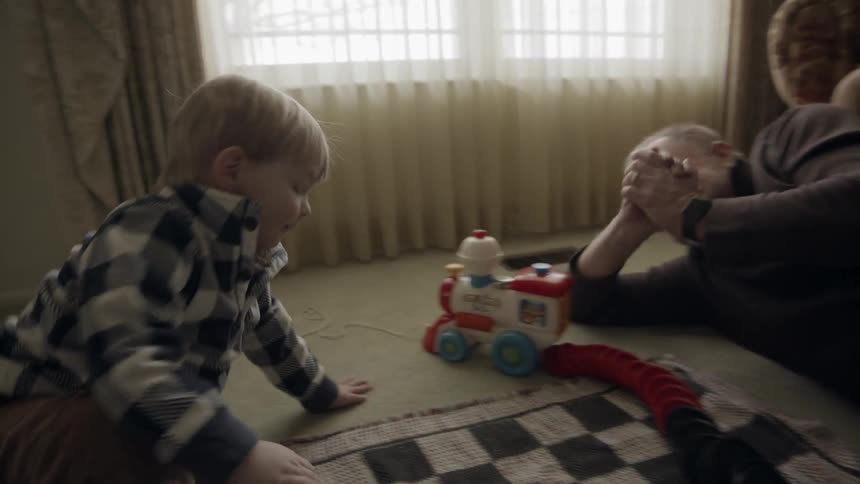 A man and young child play on the floor