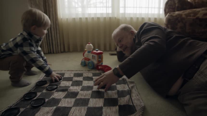 A man plays on the floor with a young child