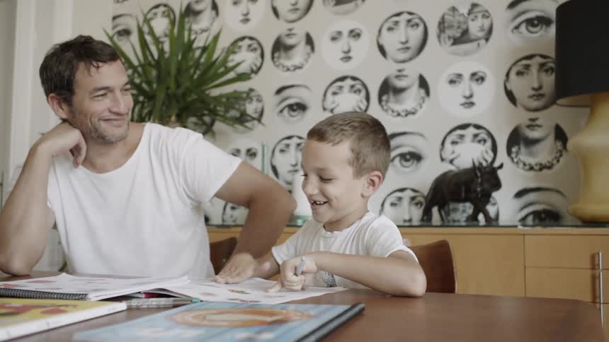 A man reads books with a young child at a table
