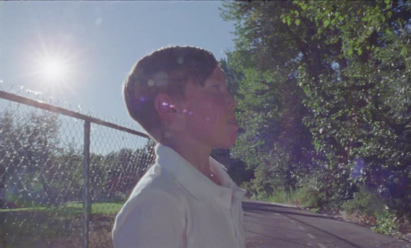 Boy stands outside on a sunny day