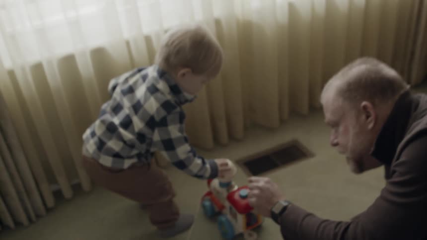 Man and young boy play on a living room floor
