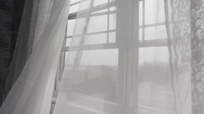 Wind blows through window curtains