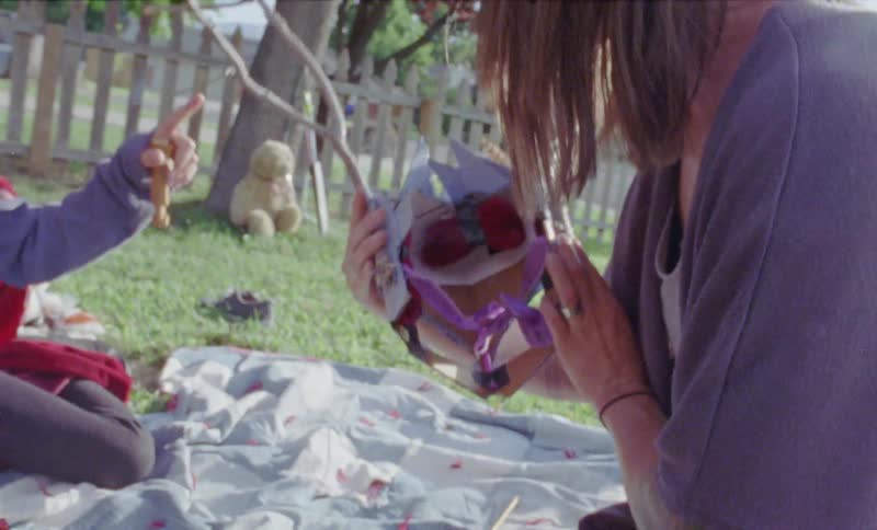 Woman shows a child a mask and puts it on his face