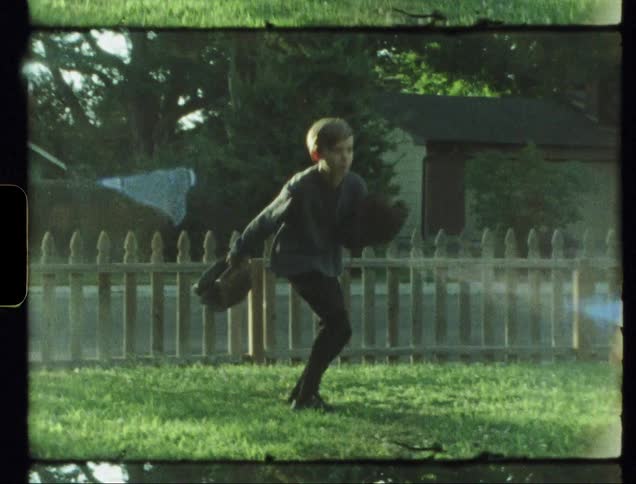Child picks up two baseball gloves in a yard and throws one