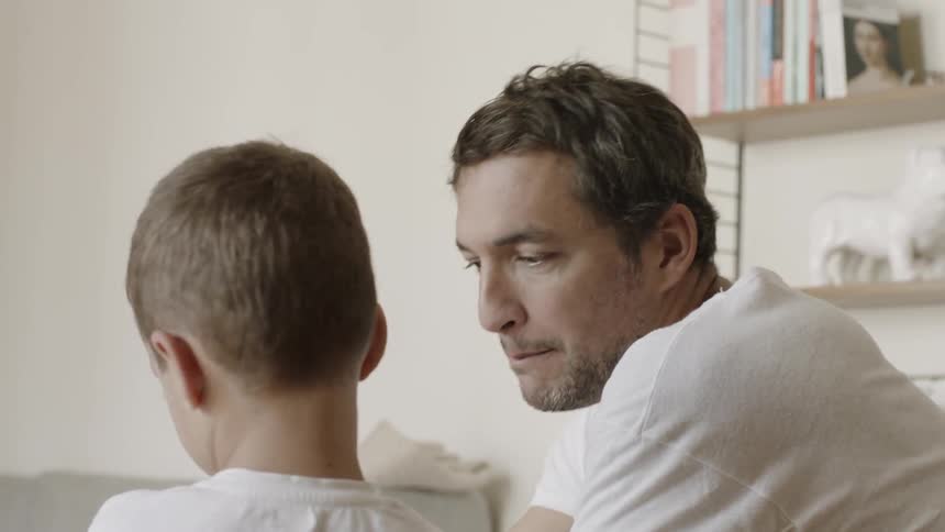 A man talks to a young boy inside the house