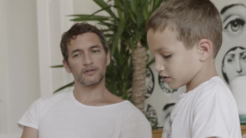 A dad listens as his son points and reads to him