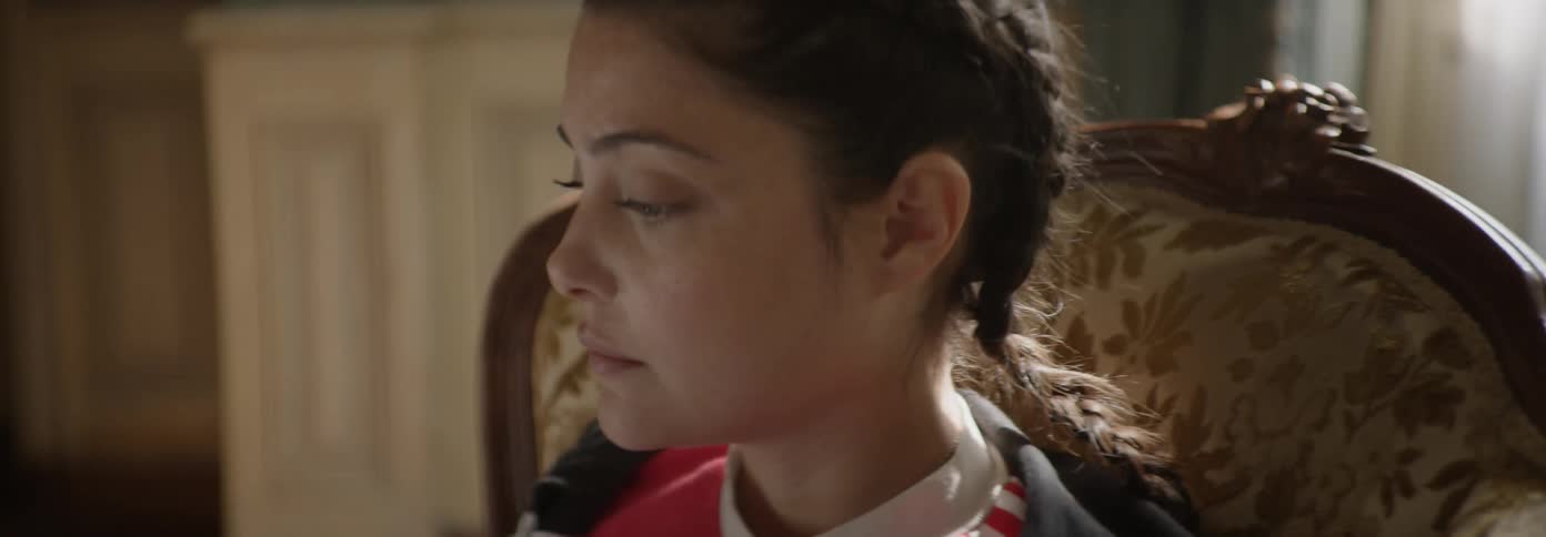 Girl sits in a chair looking downward