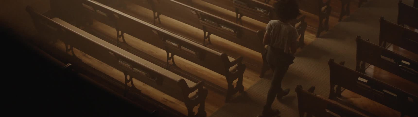 Woman walks down aisle in between church pews